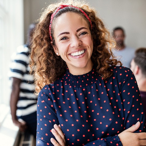 Woman in polka-dot shirt smiling with her arms folded