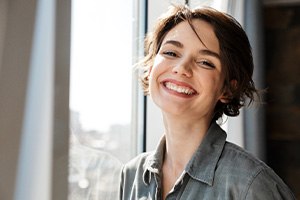 Woman standing next to window and smiling