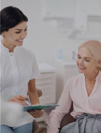 Dental team member holding a clipboard while talking to a dental patient