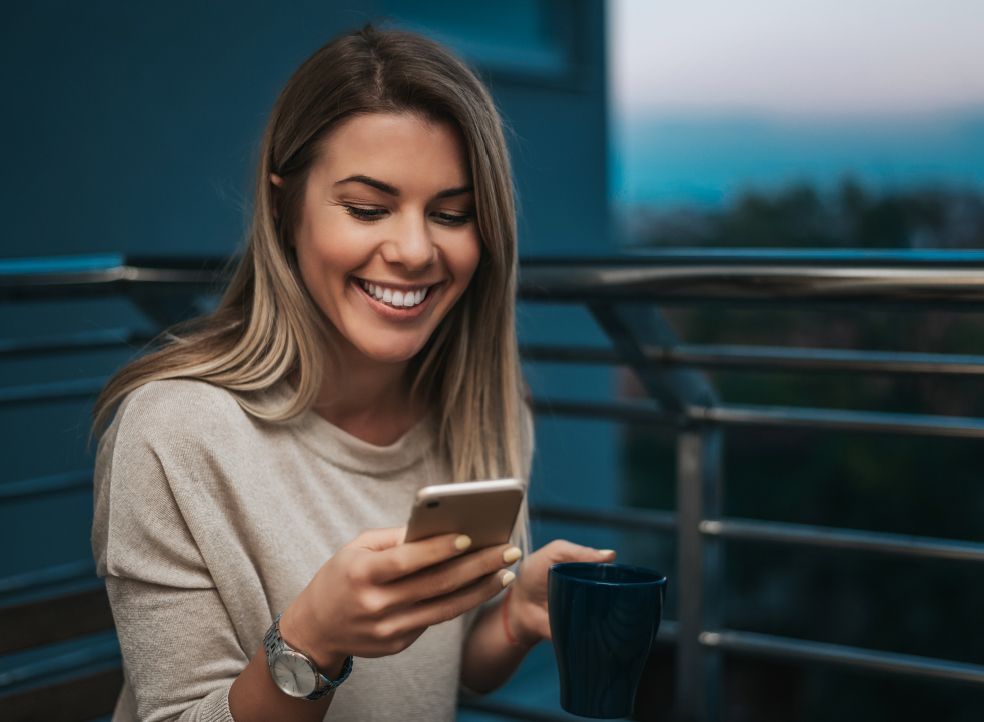 Woman smiling while looking at her smartphone